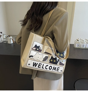 Detail of canvas cat tote bag featuring comic style prints and welcome text on a beige base