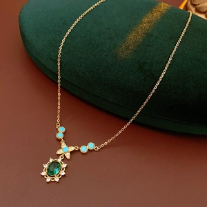 Détail d'un collier vintage doré avec pierre d'émeraude et accents turquoise