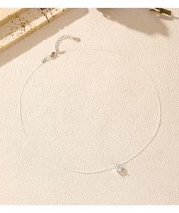 Detail of invisible fishing line necklace with a single round Moissanite diamond pendant
