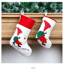 Detail of embroidered Santa stockings hanging on a wooden mantle with pine branches