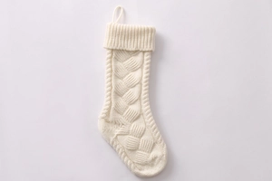 Close-up of white cable knit Christmas stocking with hanging loop on white background