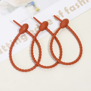 Close-up of three matte orange silicone cable ties with adjustable gear structure