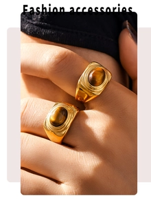 Close-up of vintage gold oval tiger eye rings featuring textured bands on a hand
