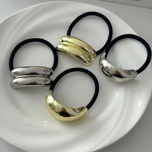 Minimalist geometric metal hair tie set with gold and silver finishes on a ceramic plate