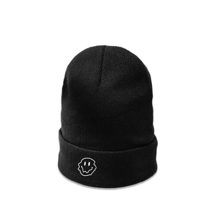 Close-up of black knitted beanie with white distorted melting smiley face embroidery