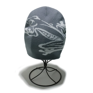 Detail of dark grey knit beanie featuring abstract lizard pattern on textured fabric