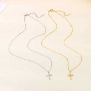 Gold and silver stainless steel cross necklaces with zircon insets on textured paper