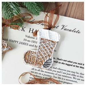 Close-up of resin gingerbread sock ornament with white embossed details and silk ribbon