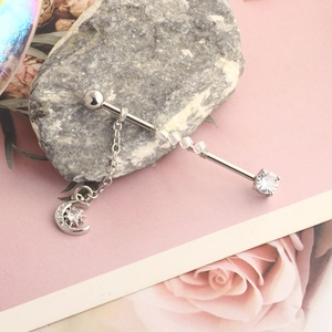 Macro detail of silver industrial barbell piercing with opal bead and moon star pendant