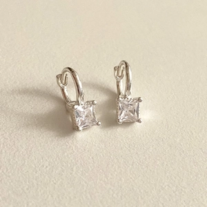Detailed view of silver hoop earrings featuring square-cut cubic zirconia in a 4-prong setting