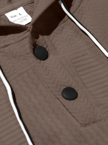Close-up of brown hoodie neckline with button detail and herringbone knit texture