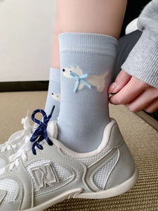 Dettaglio di calzini in maglia azzurra con motivo a cucciolo e decorazione con fiocco blu