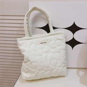 Detail of white quilted tote bag featuring floral stitching and simple wish fabric label