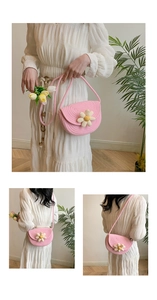 Dettaglio della borsa in paglia rosa intrecciata con margherita bianca e tracolla in cotone