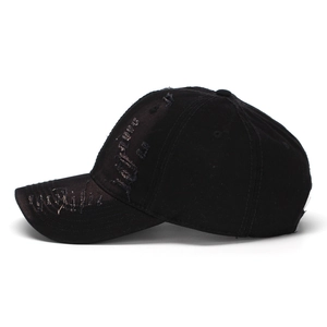 Close-up of distressed vintage black denim baseball cap with torn details and worn brim
