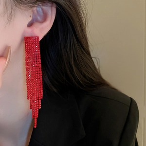 Detail of red rhinestone long tassel earrings shown as worn on a model for a luxury look