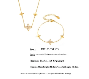 Macro shot of gold four-leaf flower jewelry set with sparkling zircon on stainless steel