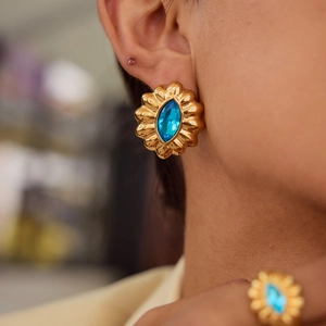 Elegant gold flower ring and earring set with a blue zircon gemstone on a model