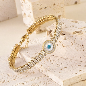 Macro shot of gold Evil Eye bracelet featuring cubic zirconia stones on stone background