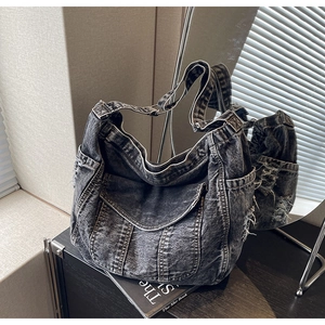 Gros plan d'un sac à bandoulière en denim noir délavé avec des bords effilochés