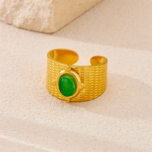 Macro detail of vintage gold-plated wide ring featuring green gemstone and mesh texture