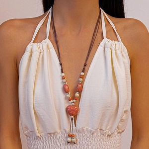 Gros plan d'un collier en céramique avec pendentif cœur rouge et perles de bohème