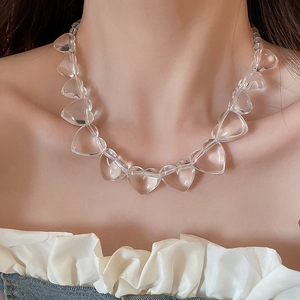 Close-up of a clear acrylic heart-shaped beaded necklace worn by a fashion model
