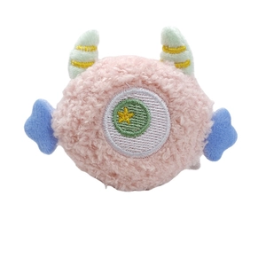 Pink plush monster brooch accessory with one eye and soft faux fur texture on white background