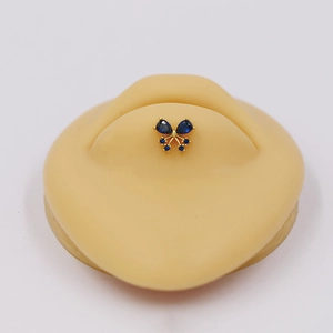 Detailed macro view of a golden butterfly labret with blue zircon on a silicone model