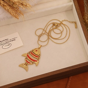 Detailed close-up of a vintage golden koi fish pendant necklace with red accents on a tray