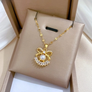 Close-up of golden bow pendant necklace with pearl and baguette-cut cubic zirconia crystals