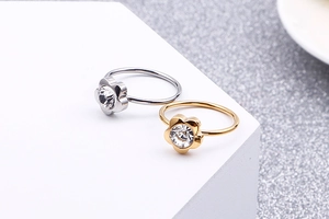 Macro detail of gold and silver flower rings with zircon stones on white display