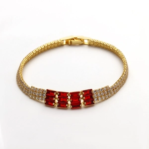 Dettaglio di bracciale dorato con quattro zirconi rossi e micro-pave di diamanti scintillanti