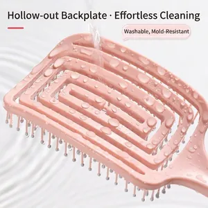 Pink vented hair brush with hollow back being washed under running water to show easy cleaning