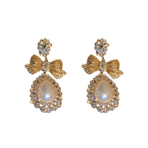 Boucles d'oreilles nœud dorées avec pierres blanches en forme de poire et cristaux
