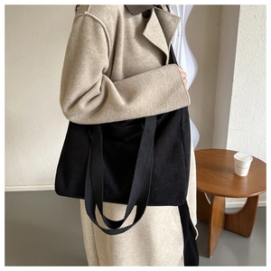 Close-up of black corduroy tote bag texture worn with a casual winter camel wool coat