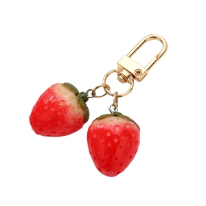 Cute resin strawberry keychain pendant with golden metal clasp on white background