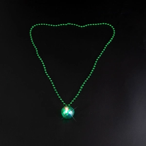 Detailed view of a glowing green disco ball pendant necklace on a dark background