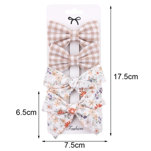 Set of four bow hair clips with beige plaid and floral patterns on white card