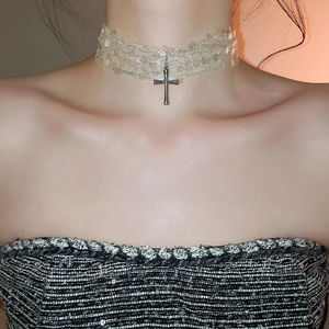 Gros plan du collier ras-du-cou en dentelle avec pendentif croix argentée et paillettes