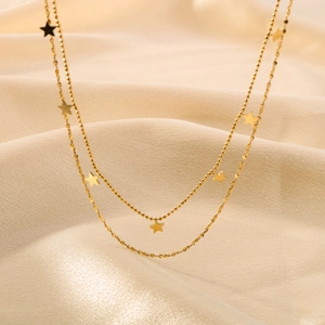 Close-up of a double-layered 18k gold plated star pendant necklace on beige silk fabric