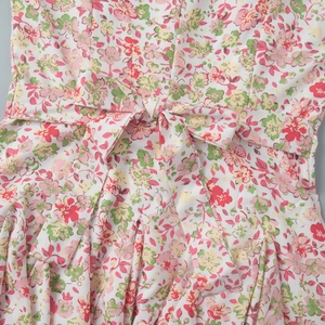 Detailed close-up of floral print dress featuring waist tie-up bow and fabric texture