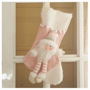Detailed view of pink knitted Christmas stocking with a plush 3D Santa gnome hanging on a window