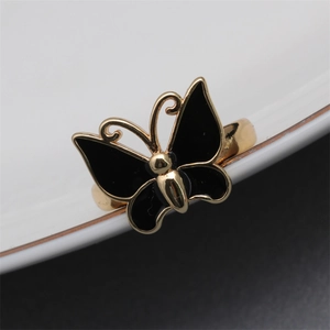 Macro shot of gold-plated butterfly ring with black enamel dripping and metallic texture