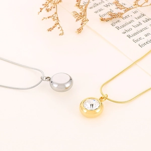 Close-up of gold and silver round pendant necklaces with cubic zirconia on snake chain