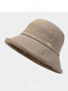 Détail d'un chapeau bob kaki clair avec tissu en sergé et petite plaque logo en métal doré