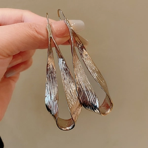 Detail view of gold geometric earrings featuring a unique hammered texture and twisted design