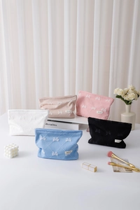Dettaglio di cinque pochette per cosmetici con motivi a fiocco in vari colori pastello