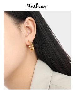 Close-up of golden beaded hoop earrings featuring matte and polished spheres