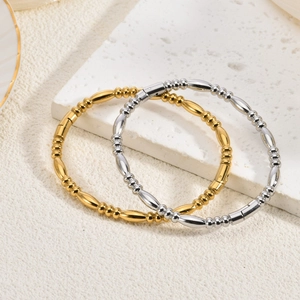 Detailansicht von 18K Gold- und Silberperlenarmbändern auf einer weißen Steinplatte